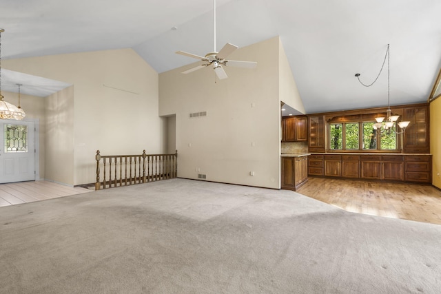 unfurnished living room with high vaulted ceiling, visible vents, baseboards, light colored carpet, and ceiling fan with notable chandelier