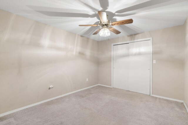 unfurnished bedroom with baseboards, a ceiling fan, carpet floors, and a closet