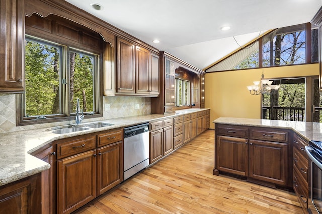 kitchen featuring lofted ceiling, a sink, light wood-style floors, stainless steel appliances, and a notable chandelier