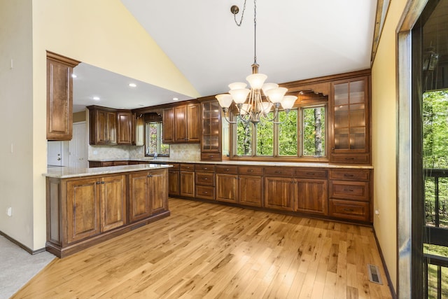 kitchen with lofted ceiling, tasteful backsplash, visible vents, light wood-style floors, and a notable chandelier