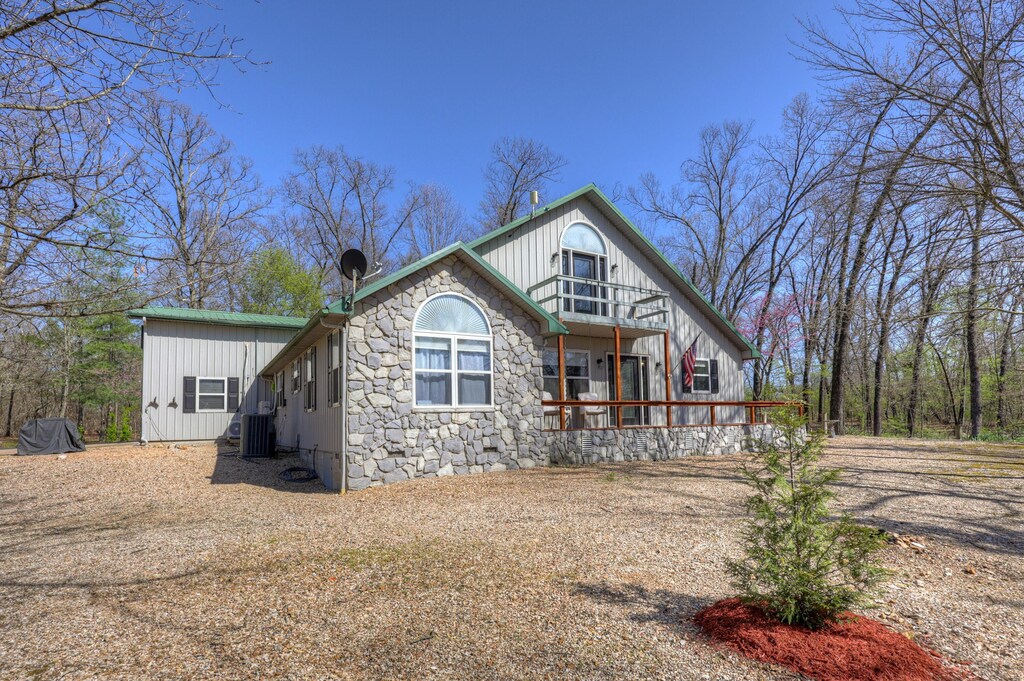 13098 Cody Ln, Diamond, MO 64840 - rear view of house with cooling unit, board and batten siding, stone siding, and a porch