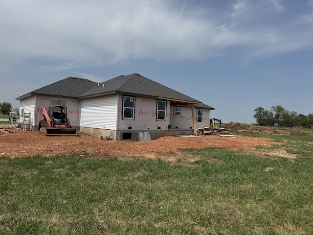 rear view of property with roof with shingles, a yard, and an attached garage