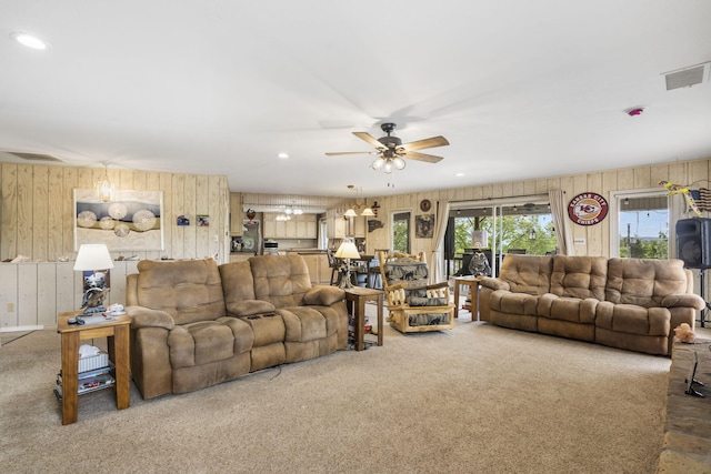 living room with wooden walls, carpet flooring, ceiling fan, and visible vents