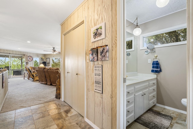 hallway featuring recessed lighting, stone finish floor, light colored carpet, and baseboards