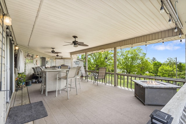 view of patio / terrace with an outdoor fire pit, an outdoor structure, a shed, outdoor dry bar, and a ceiling fan