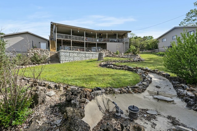 rear view of house with a lawn, stairway, and fence