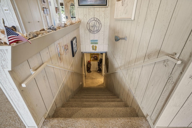 staircase featuring wood walls