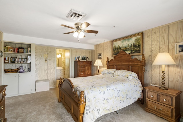 carpeted bedroom with visible vents, ceiling fan, and wooden walls
