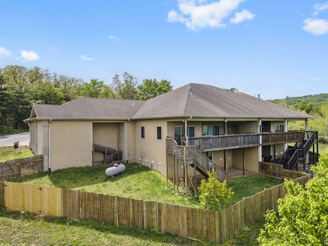 back of house with a deck, a fenced backyard, a lawn, and stairs