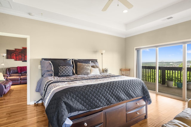 bedroom featuring access to outside, a raised ceiling, visible vents, ornamental molding, and wood finished floors