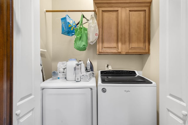 clothes washing area featuring independent washer and dryer and cabinet space