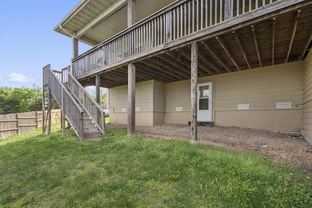 rear view of house with a lawn, a wooden deck, stairway, and fence
