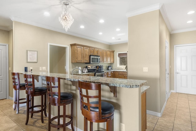 kitchen featuring appliances with stainless steel finishes, light tile patterned floors, crown molding, and a kitchen breakfast bar