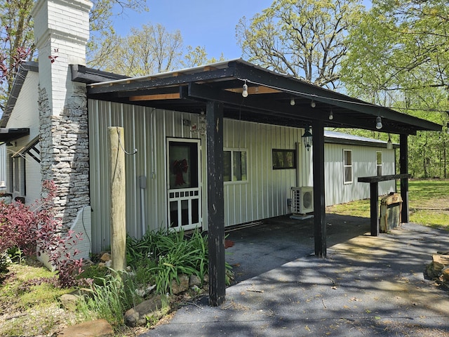 exterior space with board and batten siding, a carport, ac unit, and a chimney