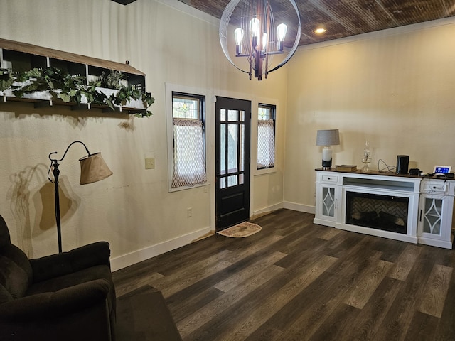 foyer entrance featuring dark wood finished floors, wooden ceiling, a chandelier, baseboards, and crown molding