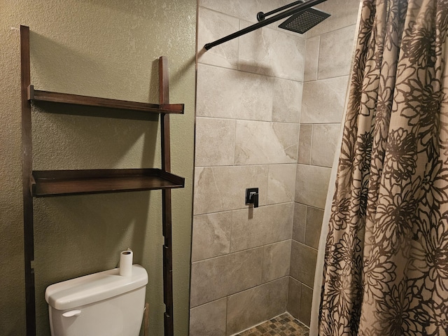 full bath with a stall shower, toilet, and a textured wall