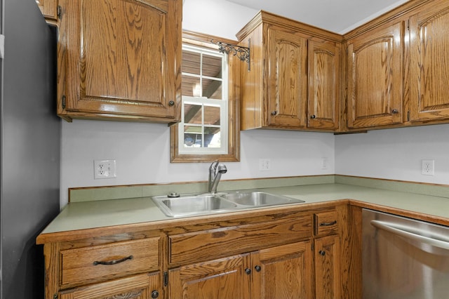 kitchen with stainless steel dishwasher, brown cabinetry, a sink, and light countertops
