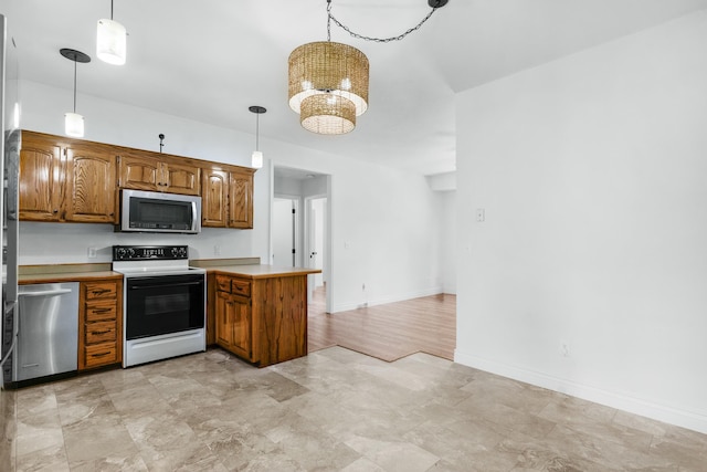 kitchen featuring light countertops, a chandelier, brown cabinetry, stainless steel appliances, and a peninsula