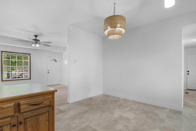 unfurnished room featuring baseboards and ceiling fan with notable chandelier