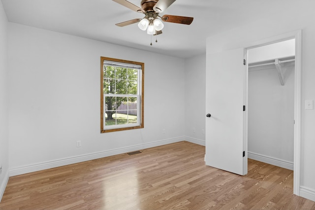 unfurnished bedroom featuring a walk in closet, visible vents, baseboards, a closet, and light wood-style floors