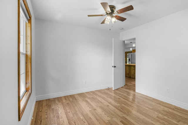 empty room featuring baseboards, a ceiling fan, and light wood-type flooring