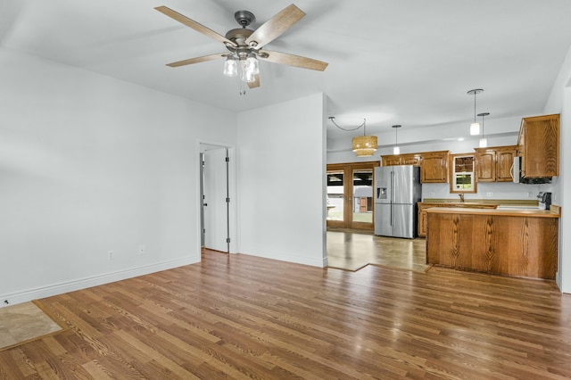 unfurnished living room featuring a ceiling fan, baseboards, and wood finished floors