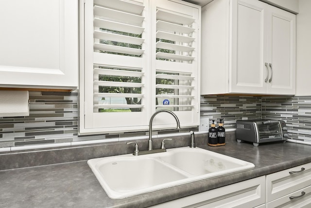 1522 S Oakland Ave, Bolivar, MO 65613 - kitchen featuring a sink, dark countertops, backsplash, and white cabinetry