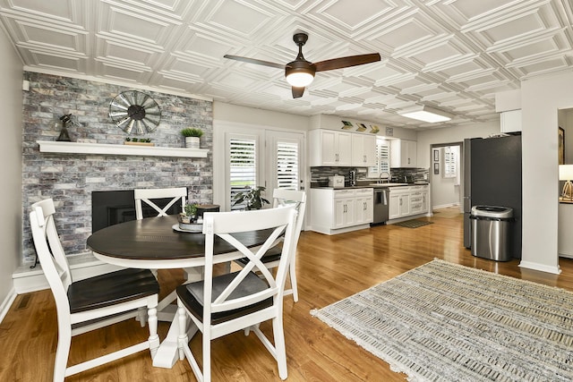 1522 S Oakland Ave, Bolivar, MO 65613 - dining area with a fireplace, an ornate ceiling, a ceiling fan, baseboards, and wood finished floors