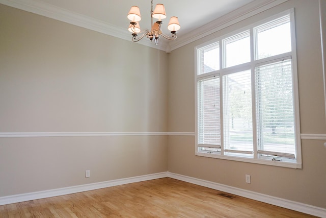 spare room featuring visible vents, ornamental molding, baseboards, light wood-style floors, and a notable chandelier