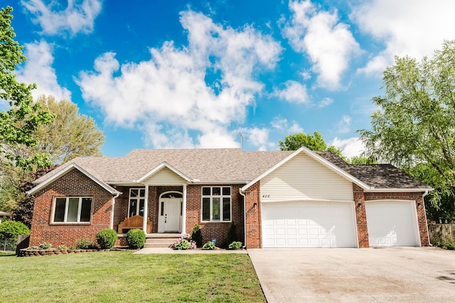 single story home with a garage, concrete driveway, a front yard, and brick siding