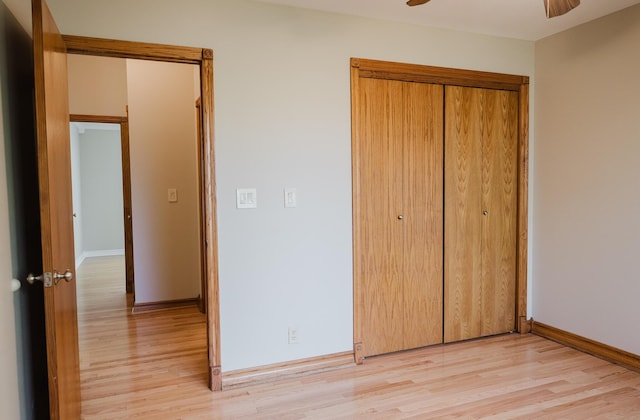 unfurnished bedroom with a closet, baseboards, a ceiling fan, and light wood-style floors