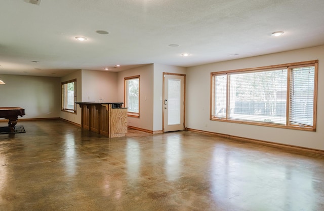 unfurnished living room featuring finished concrete flooring, baseboards, recessed lighting, and pool table