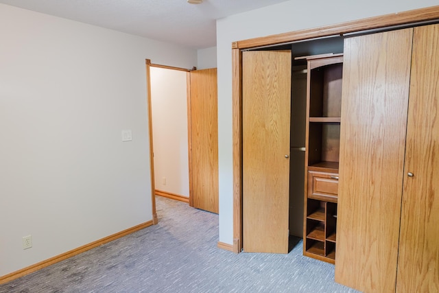 unfurnished bedroom featuring carpet flooring, baseboards, and a closet