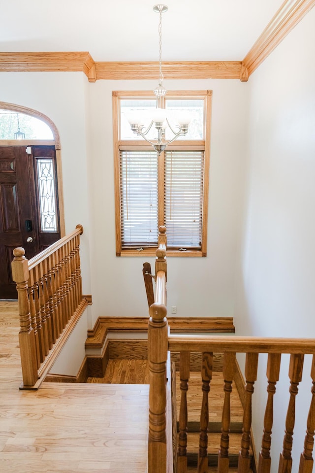 stairs featuring plenty of natural light, baseboards, wood finished floors, and a chandelier