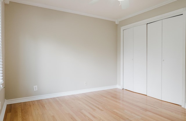unfurnished bedroom with crown molding, a closet, baseboards, light wood-type flooring, and a ceiling fan
