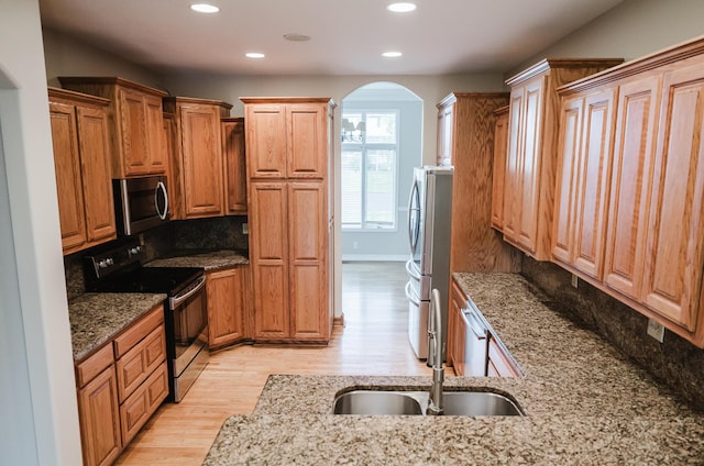406 S Cedarbrook Dr, Monett, MO 65708 - kitchen with light stone countertops, appliances with stainless steel finishes, a sink, arched walkways, and recessed lighting