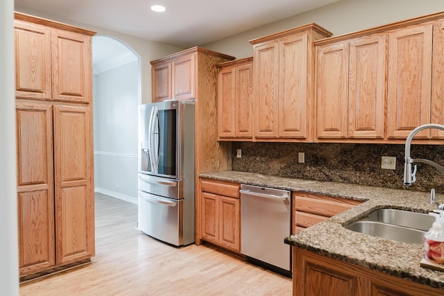 406 S Cedarbrook Dr, Monett, MO 65708 - kitchen with arched walkways, light wood-type flooring, a sink, light stone counters, and stainless steel appliances