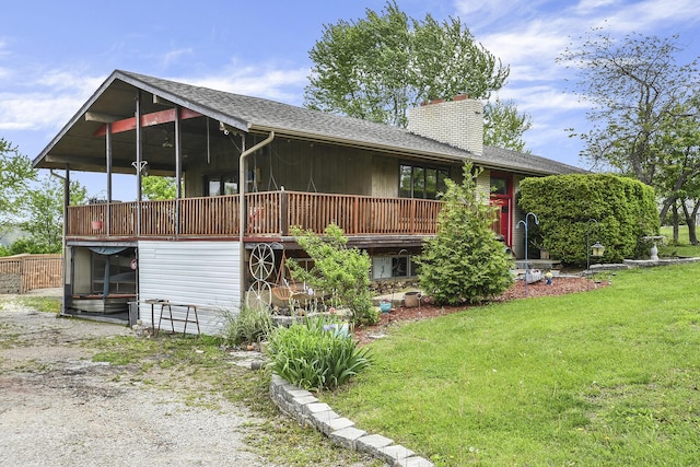 back of house featuring a lawn, a deck, a chimney, and a shingled roof