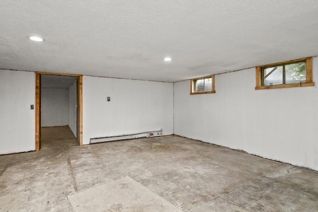 basement with recessed lighting, a textured ceiling, and a baseboard heating unit