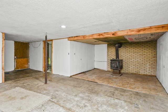 finished basement featuring a wood stove and a textured ceiling