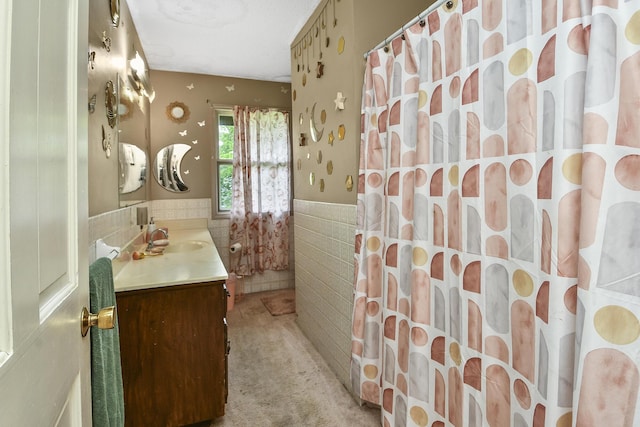 full bathroom with a shower with curtain, tile walls, a wainscoted wall, and vanity