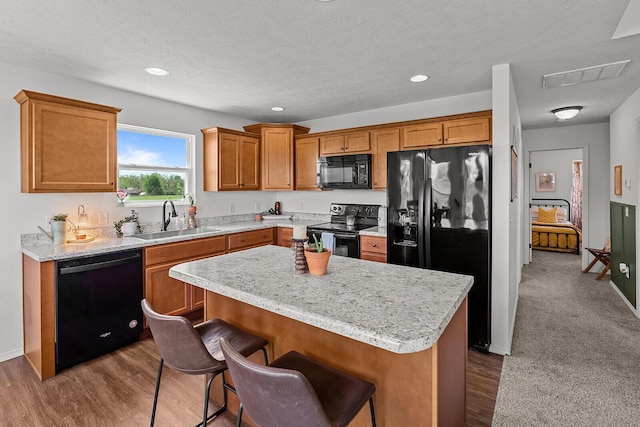 1418 S Lorraine Ave, Republic, MO 65738 - kitchen with brown cabinetry, visible vents, a center island, a sink, and black appliances