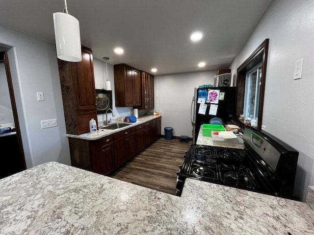 kitchen with glass insert cabinets, dark wood-style floors, light countertops, a sink, and appliances with stainless steel finishes