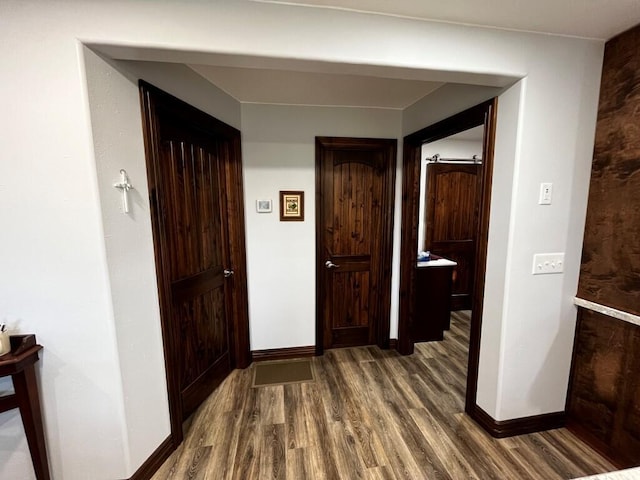 hallway featuring baseboards, wood finished floors, and visible vents