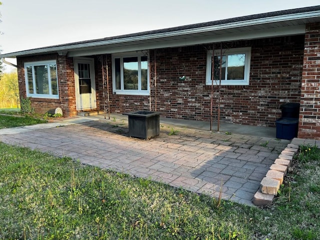 exterior space featuring brick siding and a patio area