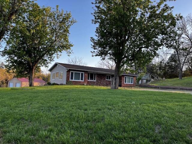 ranch-style house featuring brick siding, a front yard, and a detached garage