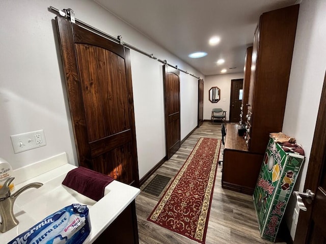 hall with recessed lighting, visible vents, a barn door, and wood finished floors