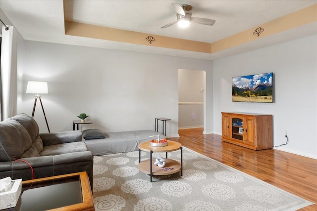 living area with baseboards, ceiling fan, and wood finished floors