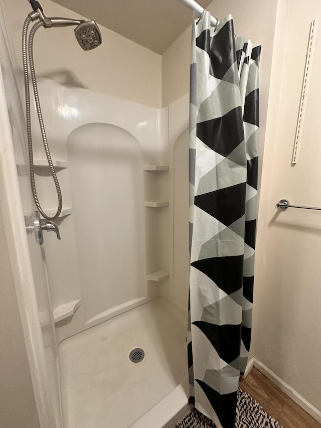 bathroom with baseboards, a shower with shower curtain, and wood finished floors