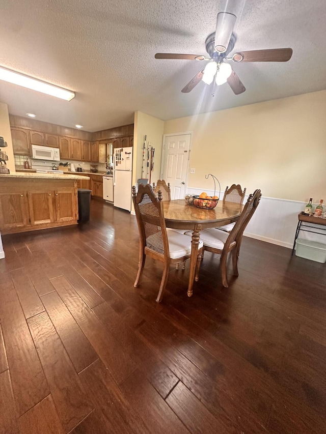 dining space featuring ceiling fan, dark wood-style flooring, and a textured ceiling